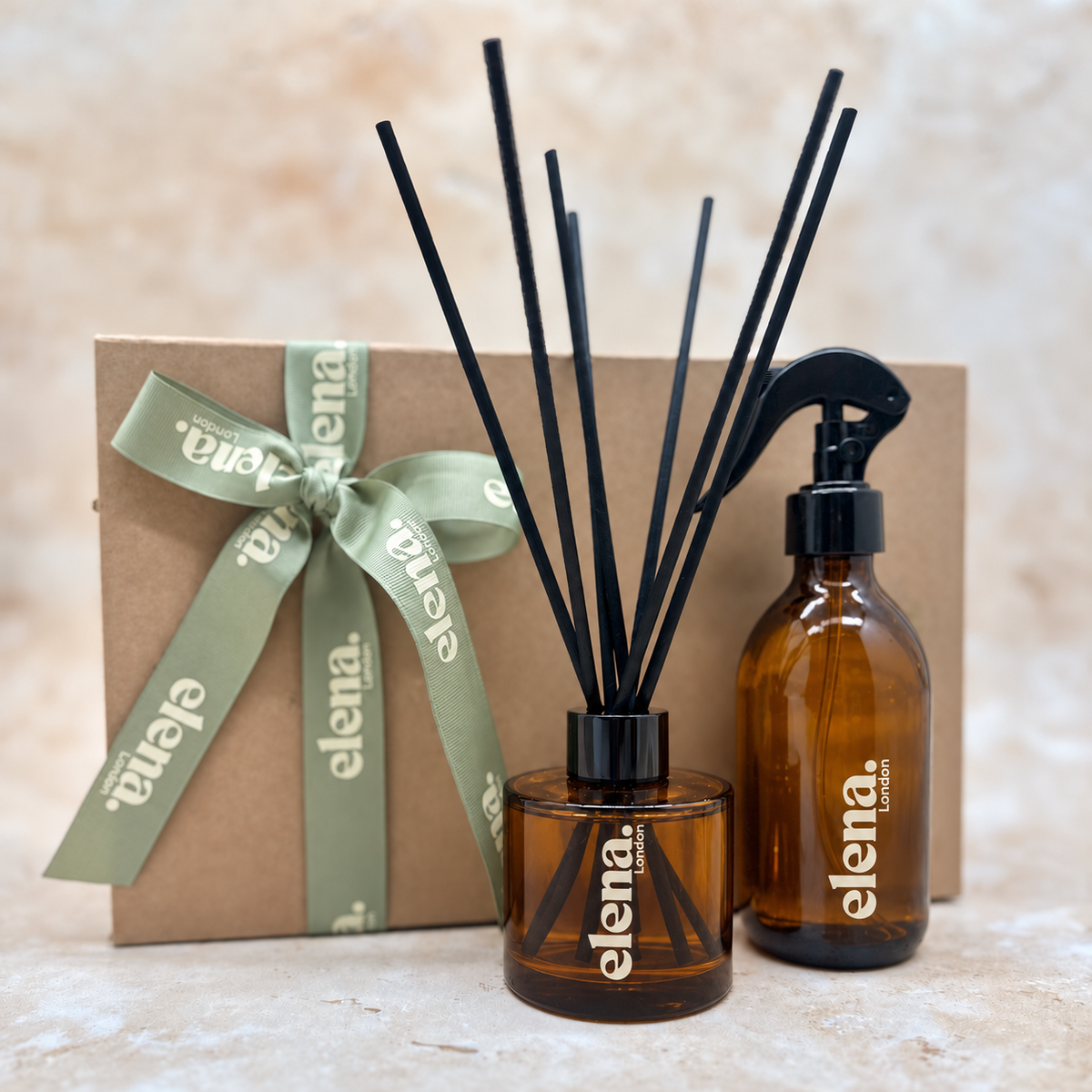 Elena London reed diffuser and matching room spray set with a brown gift box and sage green ribbon on a beige stone surface.